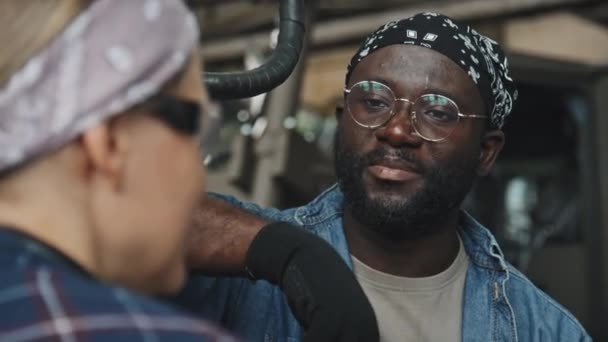 Ung Afroamerikansk Mekaniker Lyssnar Kvinnlig Kollega Medan Han Chattar Mellan — Stockvideo