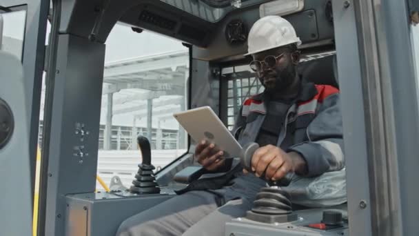 Czarny Mężczyzna Traktor Maszynista Kombinezonie Twardy Kapelusz Robi Notatki Tablecie — Wideo stockowe