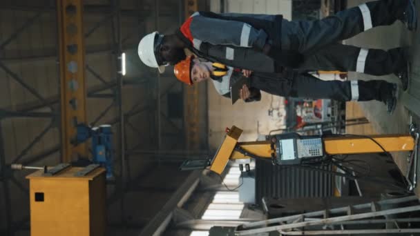 トラクター生産工場で共同作業する2人の多様な同僚の垂直撮影 — ストック動画
