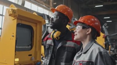 Traktör fabrikasında birlikte çalışan çok ırklı meslektaşlar vardiya sırasında sohbet ediyorlar.