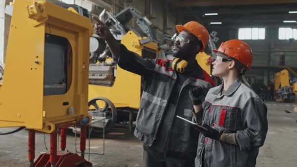 Interracial Couple Engineers Hard Hats Coveralls Looking Tractor Machine Having — Stock Video