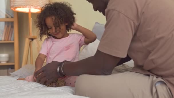 快乐的非洲裔美国父亲和他可爱的小女儿在闲暇时间在床上玩稻草球 — 图库视频影像
