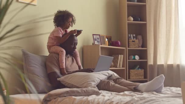 Afroamerikaner Arbeitet Laptop Bett Während Seine Jährige Tochter Auf Seinen — Stockvideo