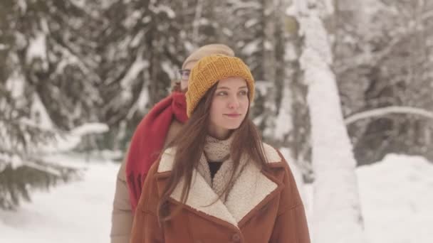 森の雪の道を散策しながら冬の風景を楽しんでいる若い多民族のグループ — ストック動画