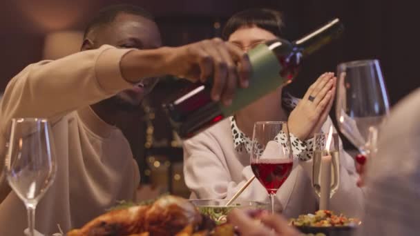 Młody Czarny Mężczyzna Nalewa Czerwone Wino Kieliszków Podczas Kolacji Przyjaciółmi — Wideo stockowe