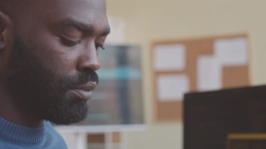Ofiste çalışırken bilgisayarda kodları yazan konsantre Afrikalı Amerikalı programcıyı kapat