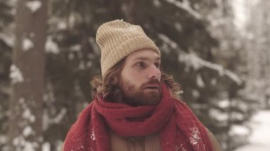 Bereli ve sıcak eşarplı yakışıklı, sakallı beyaz adamın portresi. Kışın açık havada kameraya gülümsüyor.