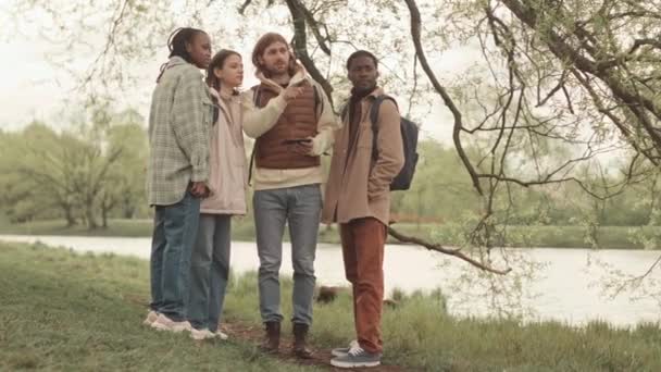 Four Young Multiethnic Friends Communicating While Walking Quiet Park Springtime — Stock Video