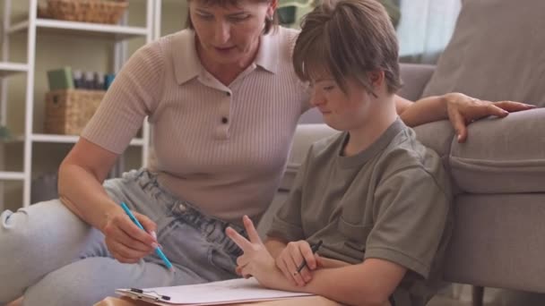 Madre Cariñosa Cuidando Hija Con Síndrome Con Dibujo Sentados Juntos — Vídeo de stock