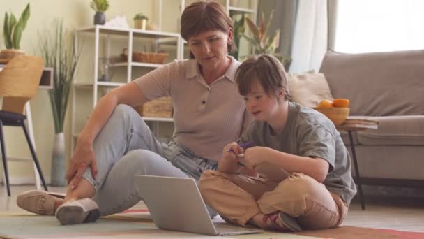 一个白人女孩 和她的母亲坐在客厅的地板上 用笔记本电脑在网上学习 — 图库视频影像