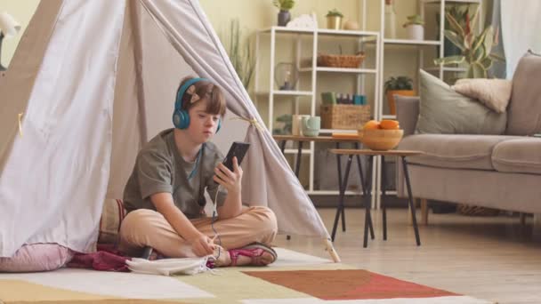 白人少女抑郁症状患者在家里休息的时候 一边听耳机里的音乐 一边用智能手机 — 图库视频影像