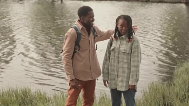 若い幸せなアフリカ系アメリカ人のカップルは 春に公園で水の上に立って会話をする — ストック動画