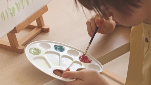 Skoncentrowana Dziewczyna Zespołem Puchowym Mieszająca Farby Palecie Podczas Malowania Kwiatów — Wideo stockowe