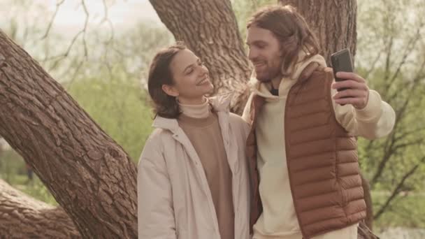 Genç Beyaz Çift Bahar Zamanı Parkta Ağaçta Beklerken Kameraya Sarılıp — Stok video