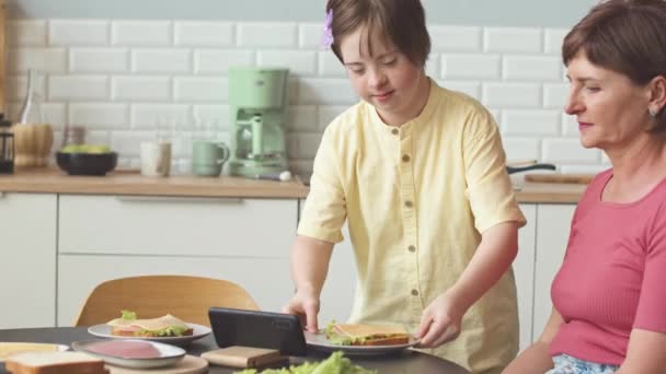 Zorgvuldig Meisje Met Syndroom Serveert Zelfgemaakte Sandwiches Tafel Tijdens Het — Stockvideo