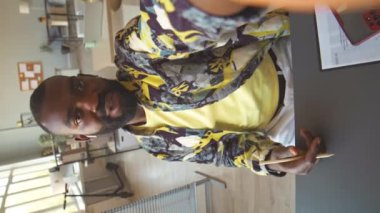 Afrika kökenli Amerikalı pazarlama uzmanının dikey el bilgisayarı, şık baskılı gömlek uzmanı, ofisteki meslektaşıyla çevrimiçi video konuşması yapıyor.