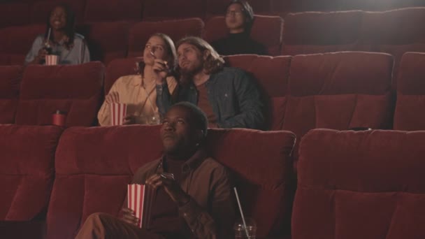 Молодые Мультиэтнические Люди Сидят Красными Креслами Кинотеатре Смотрят Захватывающие Фильмы — стоковое видео