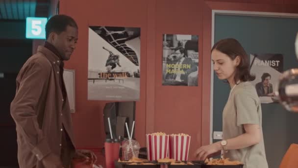 Молодий Чорний Чоловік Купує Попкорн Кінотеатрі Досить Усміхненою Дівчиною Яка — стокове відео