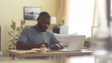 Ofis masasında dizüstü bilgisayarın önünde oturan Afro-Amerikan işadamı