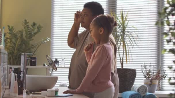 Afroamerykanka Robi Masaż Twarzy Podczas Gdy Jej Córeczka Myje Zęby — Wideo stockowe