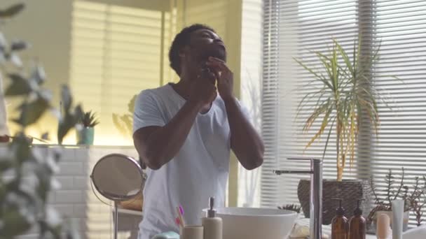 Ung Afroamerikansk Man Putsar Skägget Framför Spegeln Badrummet — Stockvideo