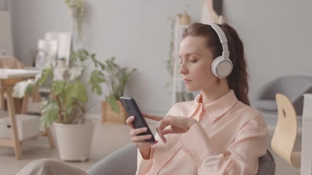Νεαρή Καυκάσια Γυναίκα Που Φοράει Ασύρματα Ακουστικά Ακούγοντας Μουσική Smartphone — Αρχείο Βίντεο