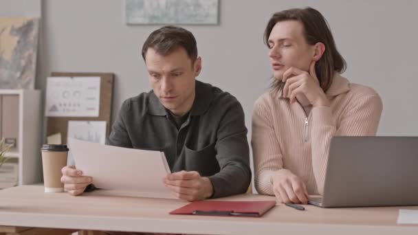 Pasangan Gay Kaukasia Melihat Melalui Dokumen Bisnis Sambil Duduk Meja — Stok Video