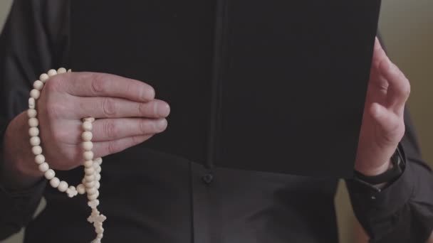 Mittelteil Der Priesterhände Die Bibel Und Rosenkranzperlen Beim Gebet Halten — Stockvideo