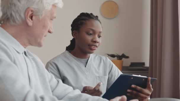 Junge Afroamerikanische Krankenschwester Kümmert Sich Hause Einen Alten Mann Aus — Stockvideo