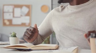 Afrika kökenli Amerikalı erkek ofis çalışanı masa toplantısı sırasında proje fikirlerini ekiple paylaşırken görüntülendi.