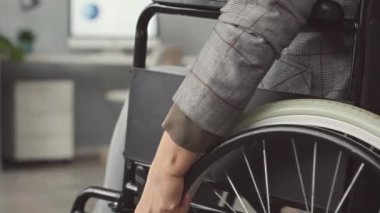 Tanımlanamayan tekerlekli sandalyedeki kadın çalışma masasına doğru gidiyor.