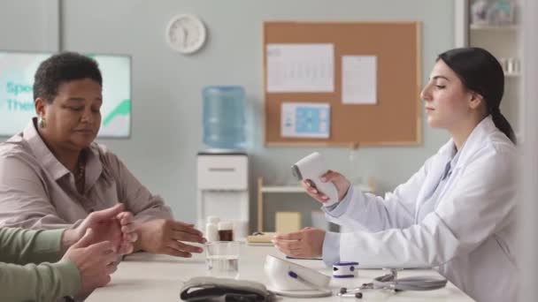비접촉식 적외선 온도계로 약속하는 노인과 여성의 온도를 측정하는 간호사 — 비디오