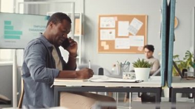 Çoklu etnik çeşitlilikte yaratıcı iş adamlarının telefon görüşmeleri yapıp bilgisayarda yazı yazarken modern ofiste bölünmüş duvarlarla birlikte çalışmalarının PAN karesi.