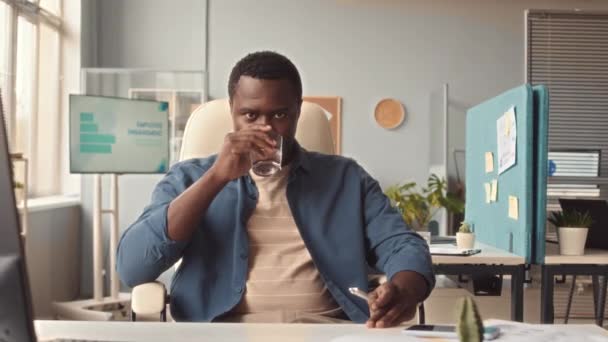 Young Black Man Drinking Glass Water Looking Camera While Sitting — Stock Video