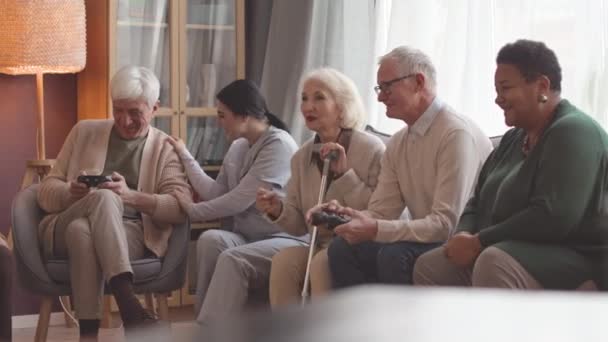 Ομάδα Εθνοτικά Διαφορετικών Boomers Και Νοσοκόμα Τους Διασκεδάζουν Παίζοντας Βιντεοπαιχνίδια — Αρχείο Βίντεο