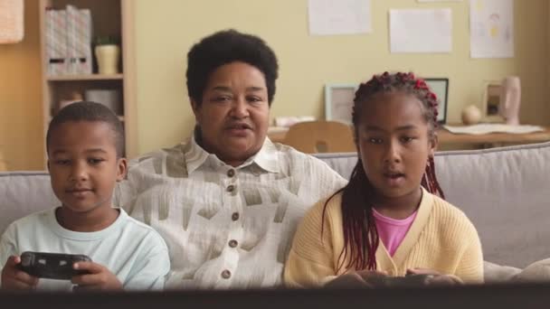 Радісна Афроамериканська Бабуся Обійняла Своїх Двох Крутих Онуків Граючи Відеоігри — стокове відео