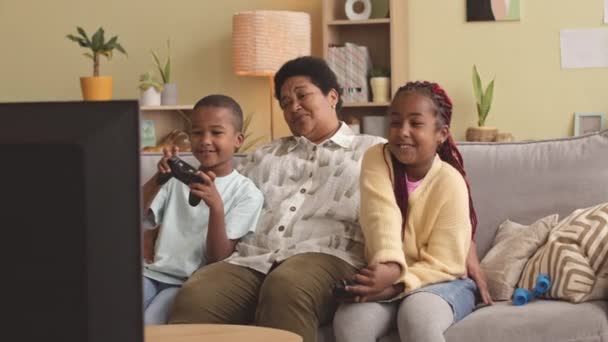 Афроамериканская Старшая Женщина Двое Внуков Играют Видеоигры Сидя Диване Уютной — стоковое видео