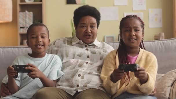 Moderne Afroamerikanische Großmutter Beobachtet Ihre Süßen Enkelkinder Bei Videospielen Und — Stockvideo