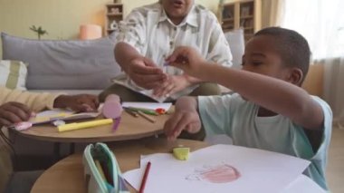 İki Afrikalı Amerikalı ergen kardeş, boş zamanlarında büyükanneleriyle resim çizerken renkli kalemler ve pastel kalemler kullanıyorlar.