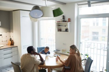 Mutfaktaki yemek masasında etnik çeşitliliğe sahip bir ailenin geniş açı sahnesi var.