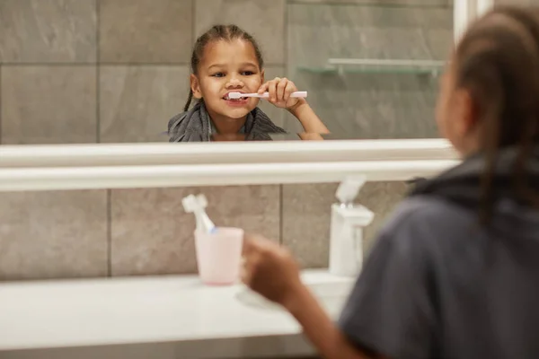 Dişlerini Fırçalayan Banyo Aynasına Bakan Tatlı Siyah Bir Kızın Portresini — Stok fotoğraf