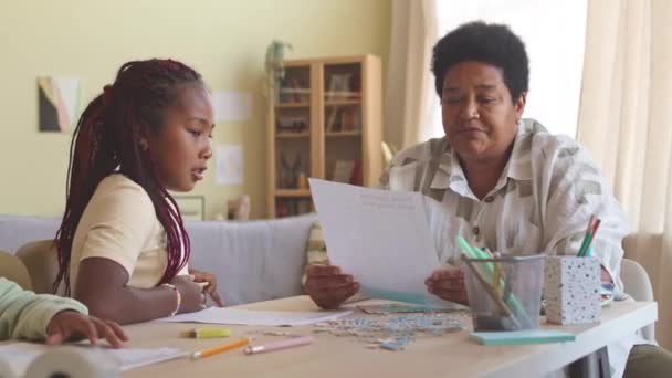 Reife Schwarze Frau Überprüft Hauszuweisung Ihrer Enkelin Während Sie Mit — Stockvideo