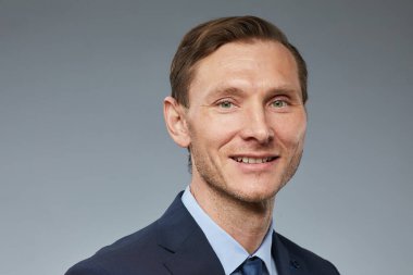 Gri arka planda kameraya bakan gülümseyen yetişkin iş adamının yakın plan portresi, boşluğu kopyala