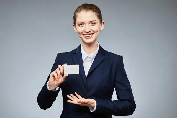 举起笑容可亲的年轻女商人的肖像 拿着空白信用卡做模型 在灰色背景的相机前展示 复制空间 — 图库照片