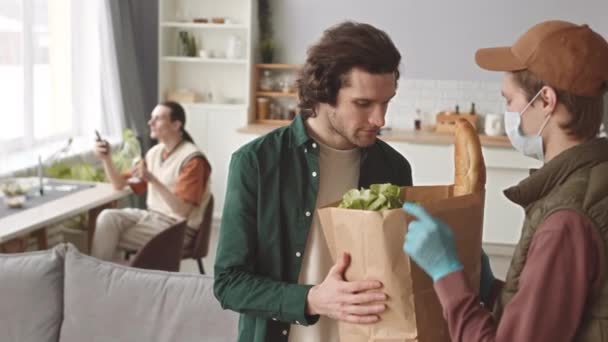 Maskierter Kurier Bringt Papiertüte Mit Frischem Gemüse Und Anderen Lebensmitteln — Stockvideo