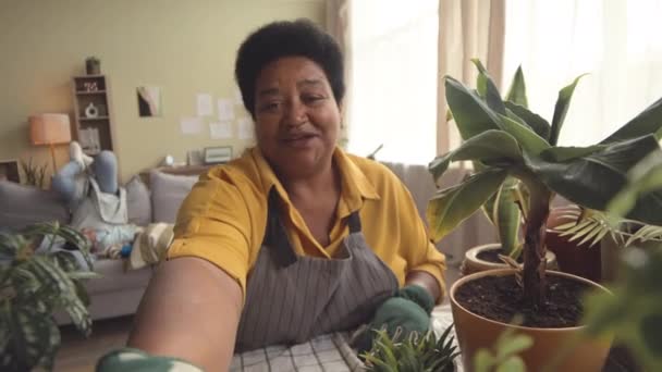 非洲裔美国人祖母在客厅里记录园艺的视频博客 而她的孙子孙女则在客厅里弹奏 — 图库视频影像