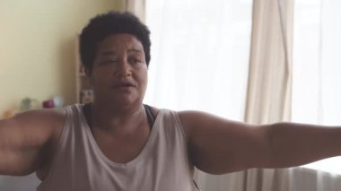 Kararlı Afrikalı Afrikalı Amerikalı kadın evde çalışırken dambıllarıyla egzersiz yapıyor.