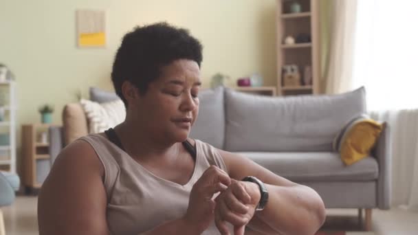 아프리카계 미국인 플러스 성숙한 여자가 집에서 훈련하는 피트니스 추적기에 그녀의 — 비디오
