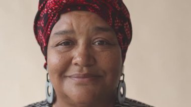 Kameraya gülümseyen başörtülü yaşlı Afrikalı Amerikalı kadının yakın plan portresi.