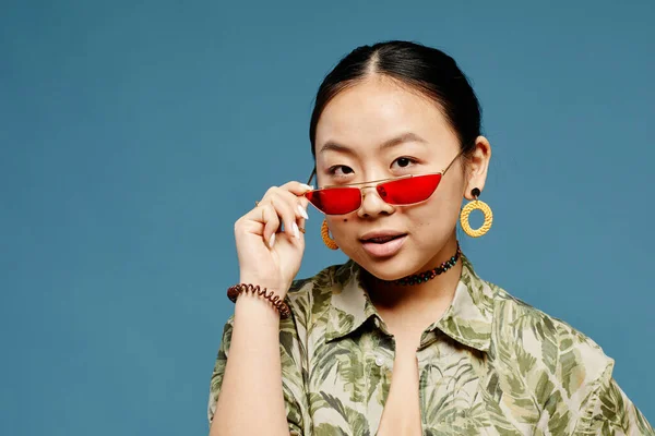 stock image Minimal portrait of Asian teenage girl wearing trendy colored sunglasses over blue background, copy space